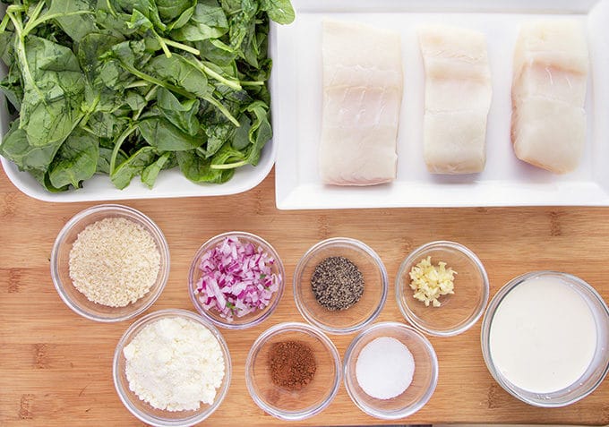 ingredients to make pan seared halibut with creamed spinach in containers sitting on a wooden cutting board