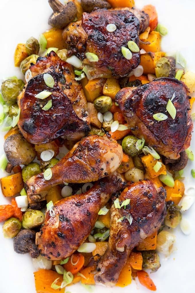 overhead shot of chai marinated chicken on a bed of roasted vegetables on a white platter