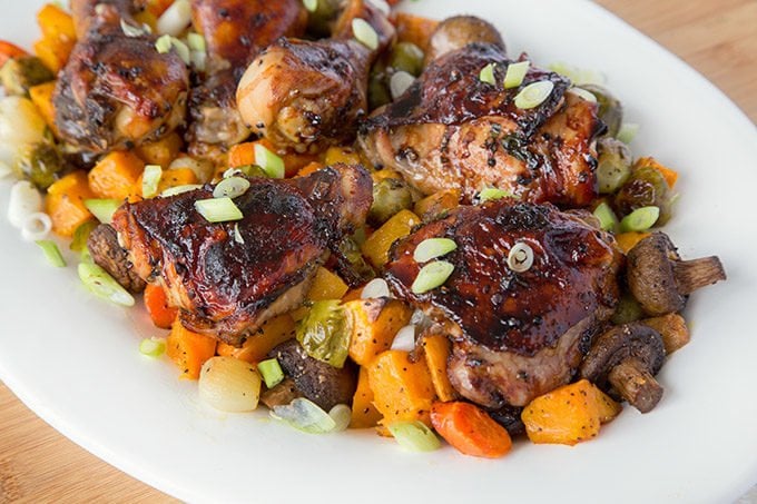 chai marinated chicken on a bed of roasted vegetables on a white platter