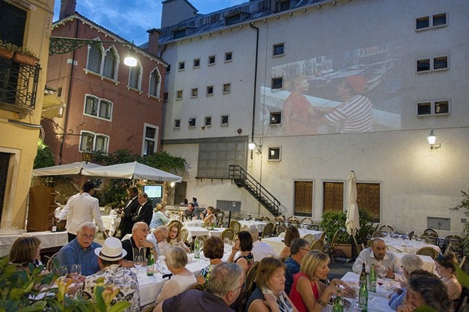 restaurant in Venice, Italy with a movie playing on a wall