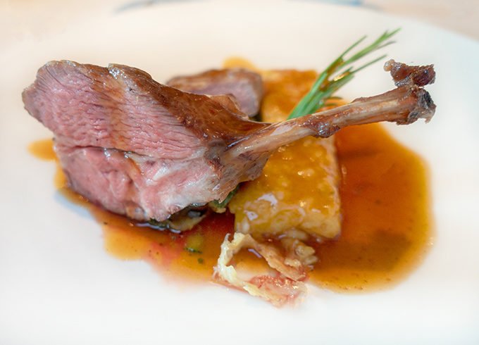 rosemary and honey glazed lamb with a demi glace on a white plate