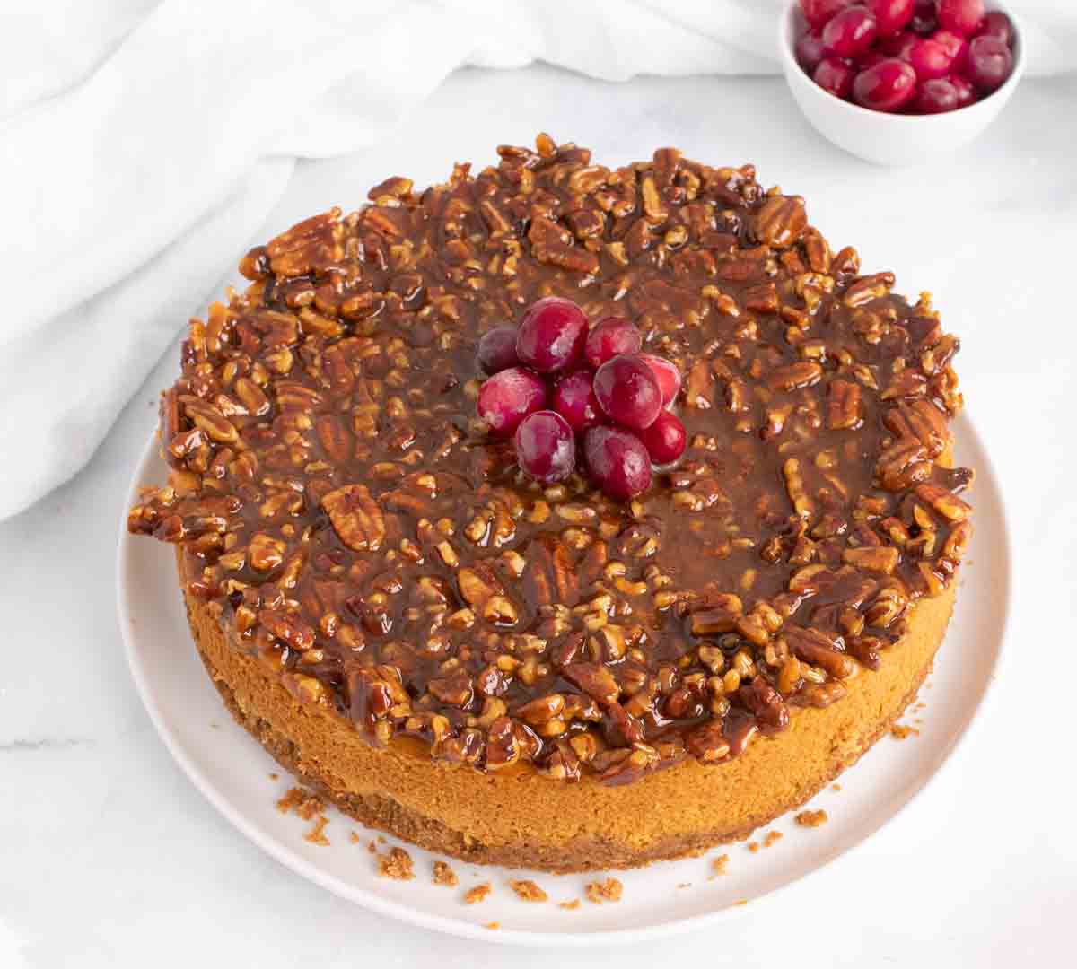 whole pumpkin praline cheesecake with cranberries on top of the cheesecake