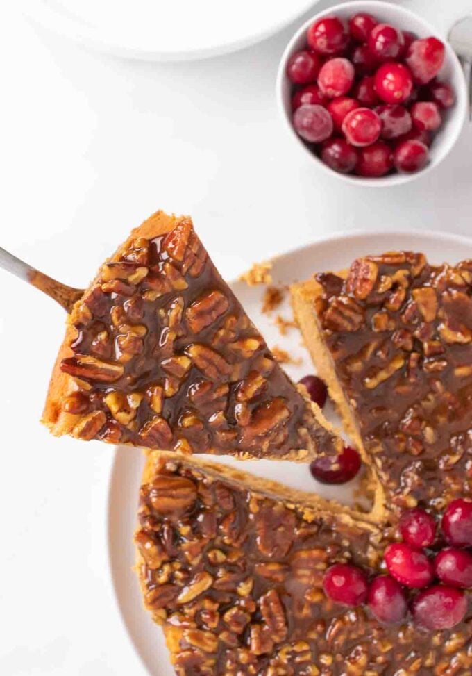 overhead view of a slice of pumpkin praline cheesecake on a cake spatula being lifted out of the cheesecake out of the cheesecake