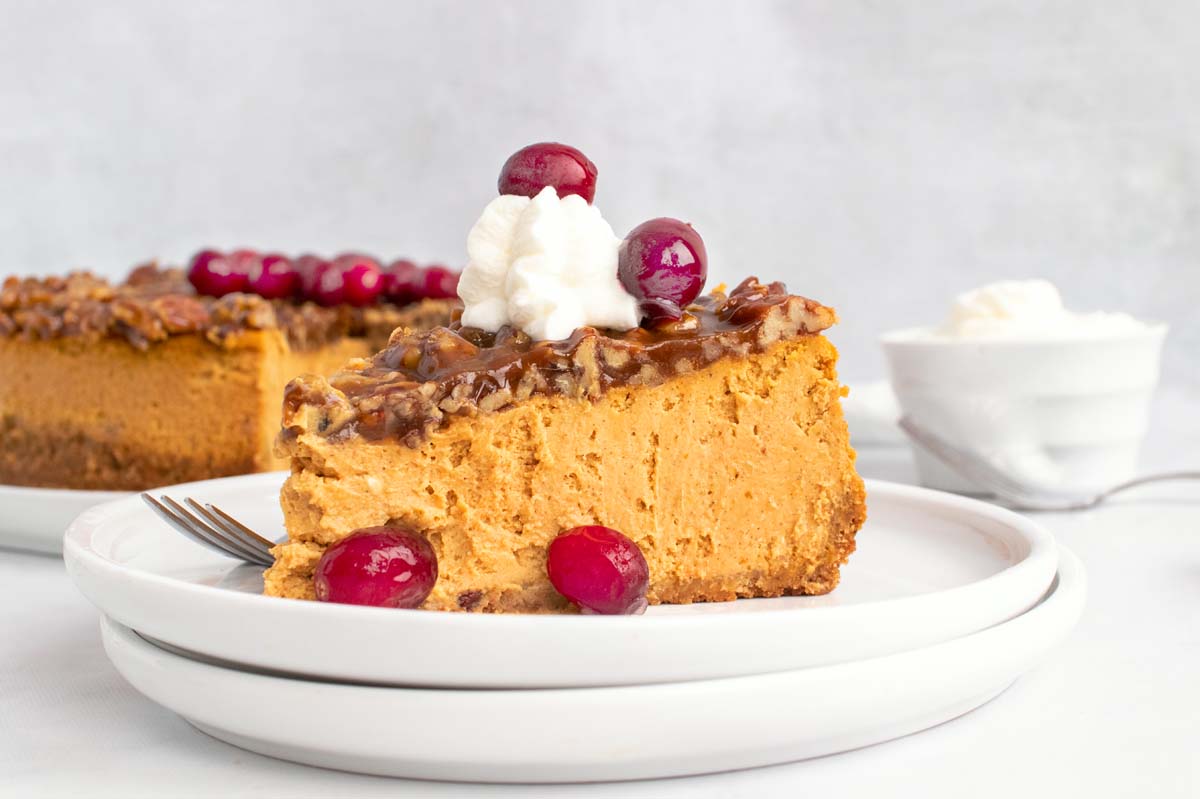 slice of pumpkin cheesecake with whipped cream and cranberries