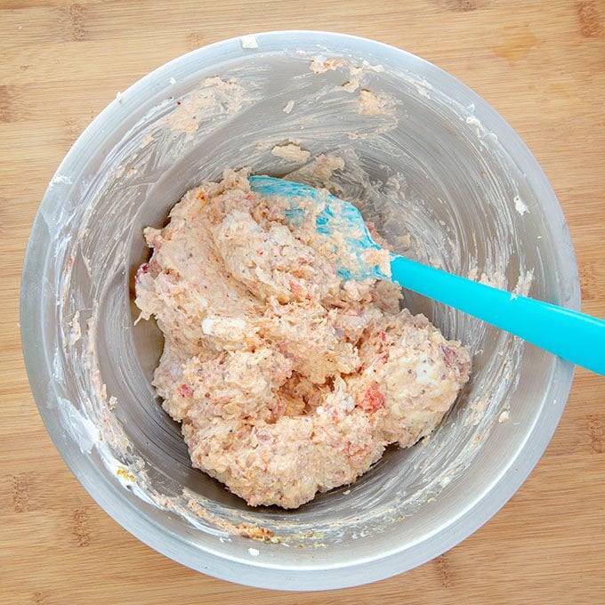 cheddar lobster dip mixed up in a stainless steel bowl with a blue spatula 