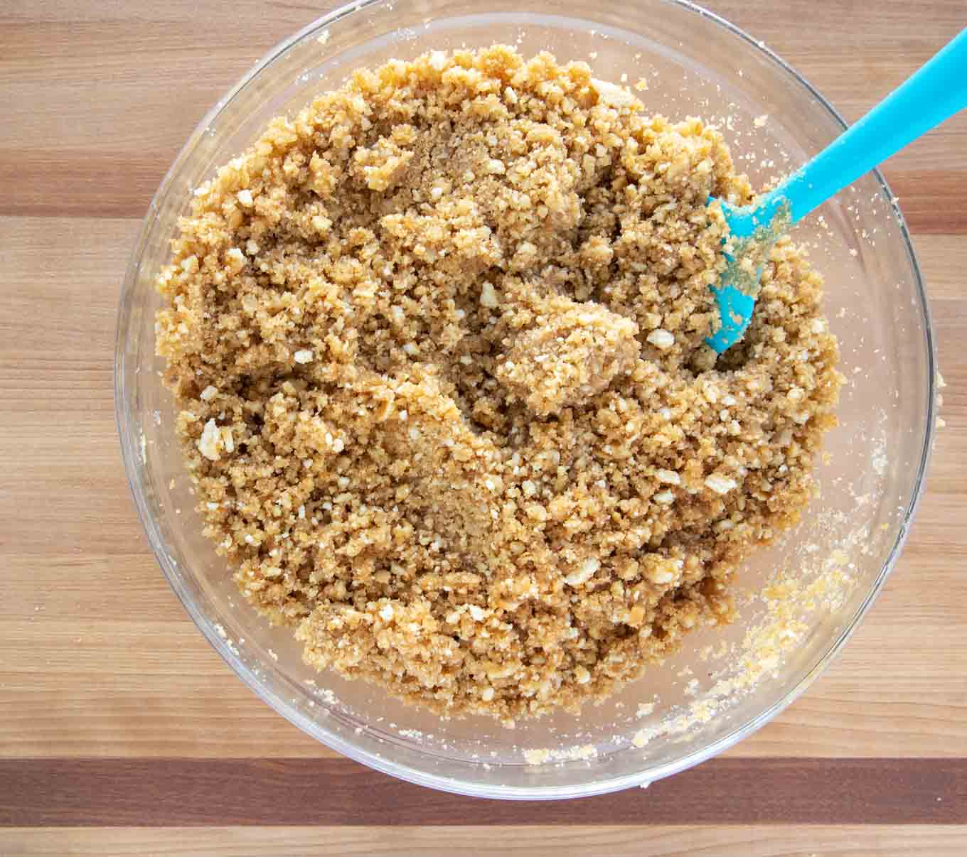 crunch topping in a glass bowl with a blue spatula