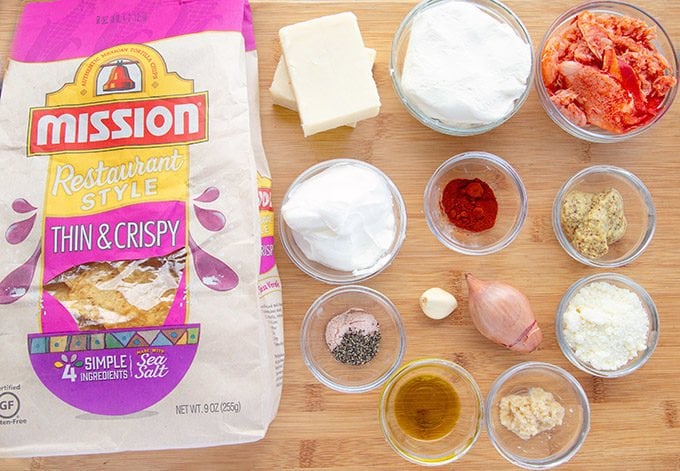 ingredients for cheddar lobster dip in glass bowls on a cutting board