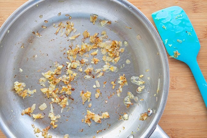 sauteed shallots and garlic in a sautee pan on a cutting board.