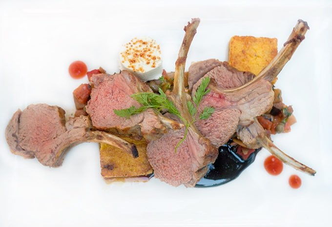 lamb chops on a white plate with demi glace