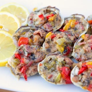 Clams Casino sitting on a white plate with lemon slices