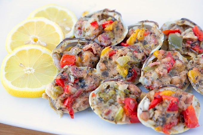 Clams Casino sitting on a white plate with lemon slices