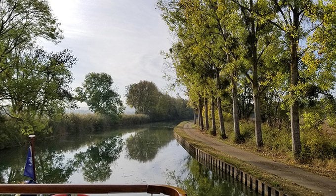 looking down the canal with trees on one side with a path 