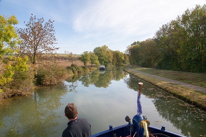 view of a man looking out onto a canal on a barge cruise