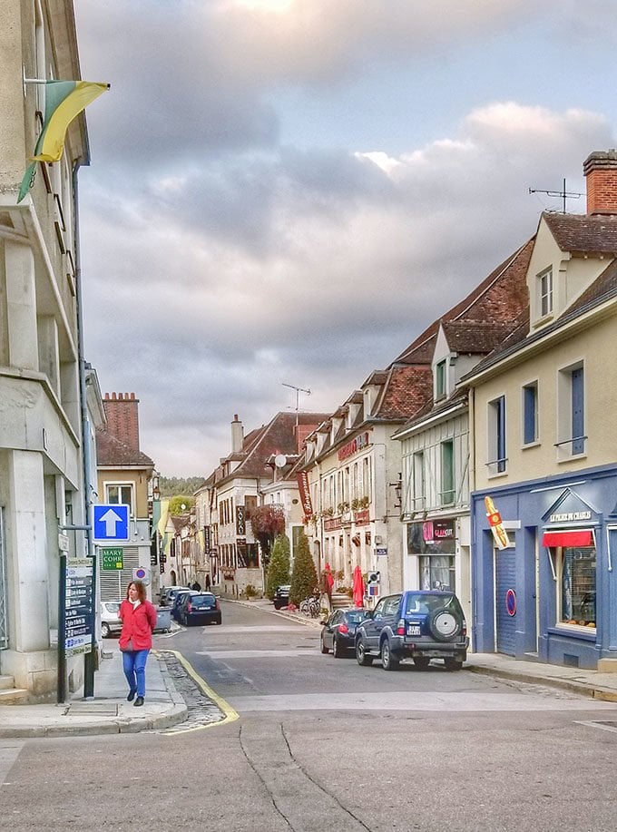 women in a red coat walking through the town of Chablis, France