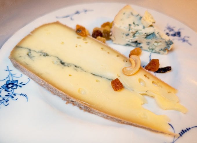 cheese on a white flowered plate with dried fruit and nuts