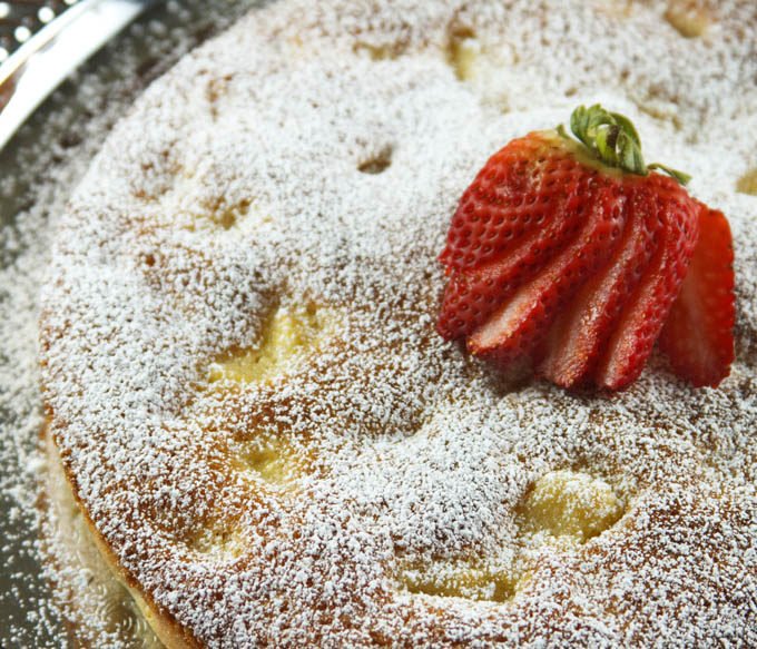 shot of whole pineapple butter cake on a silver tray with a strawberry on top