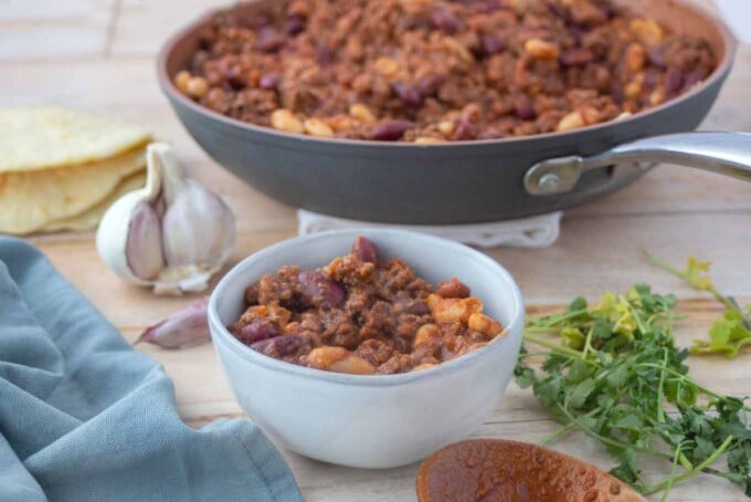 chili in a bowl with the pan of chili behind it