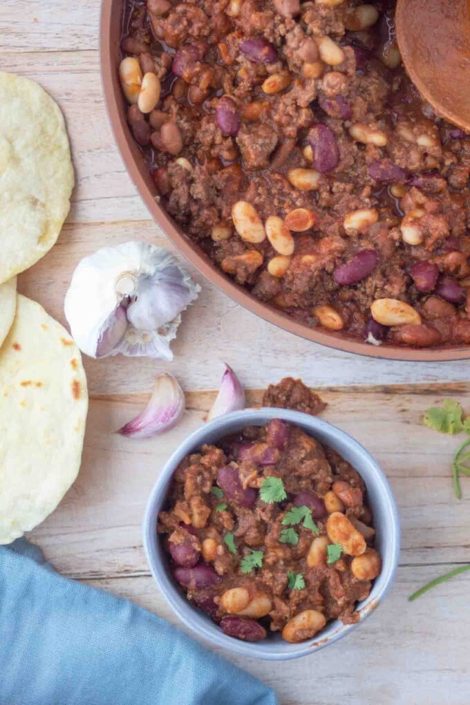 overhead view of three bean chili in a crock and pan it was made in