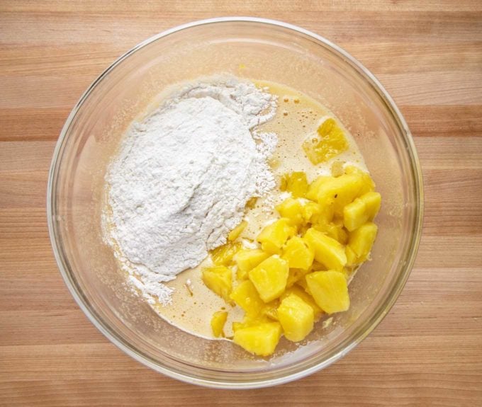 pineapple and flour mixture added to egg mixture in a glass bowl