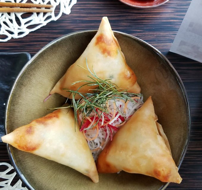deep fried scallop triangle shaped spring rolls in a brown bowl