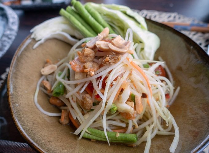 green papaya salad with peanuts in a brown bowl