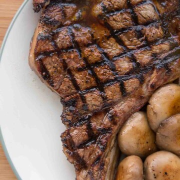 grilled ribeye with crosshatch marks on a white plate with mushrooms