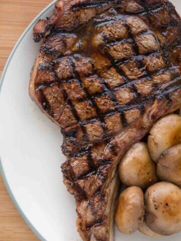 grilled ribeye with crosshatch marks on a white plate with mushrooms