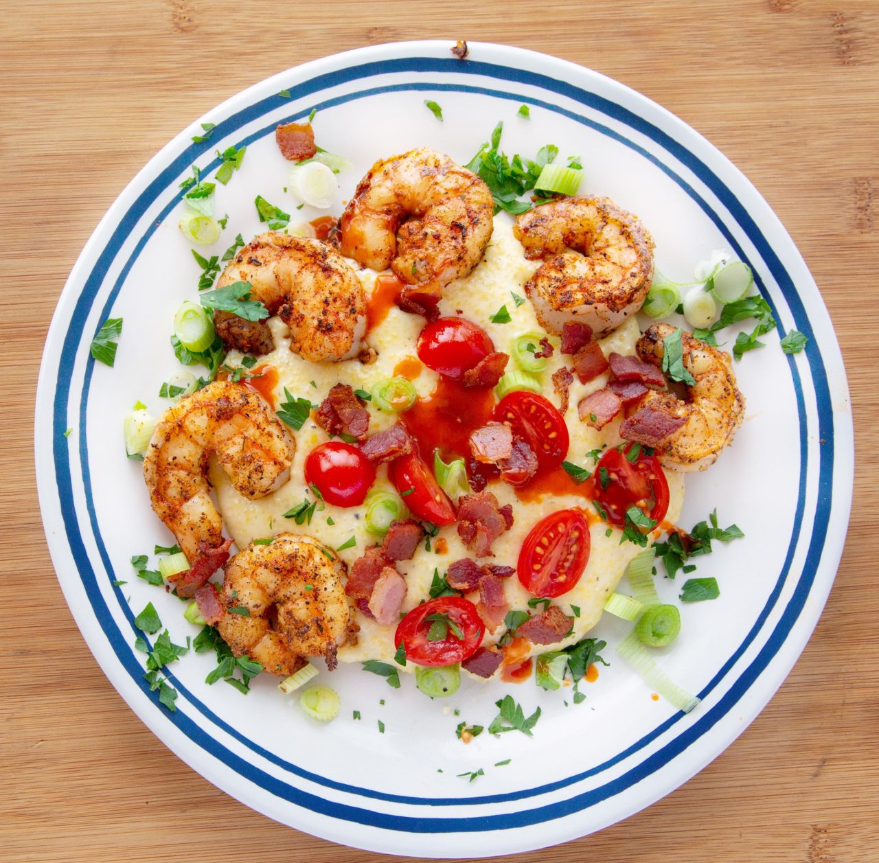 shrimp and grits on a white plate with a blue rim