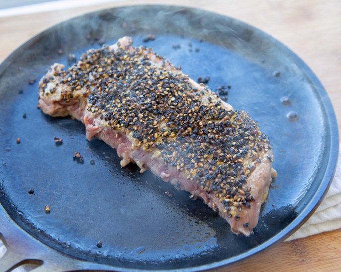 Steak au Poivre cooking on pan with smoke coming up