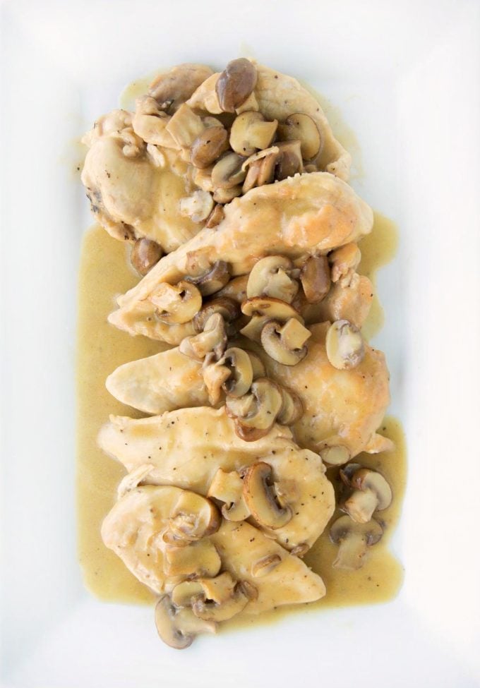 overhead shot of chicken marsala with mushrooms on a white platter
