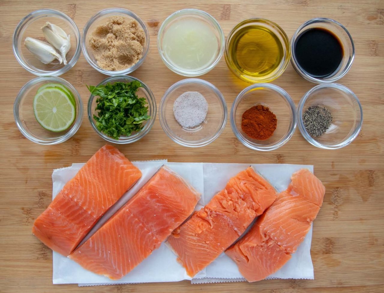 ingredients for marinade in glass bowls with salmon fillets on white paper