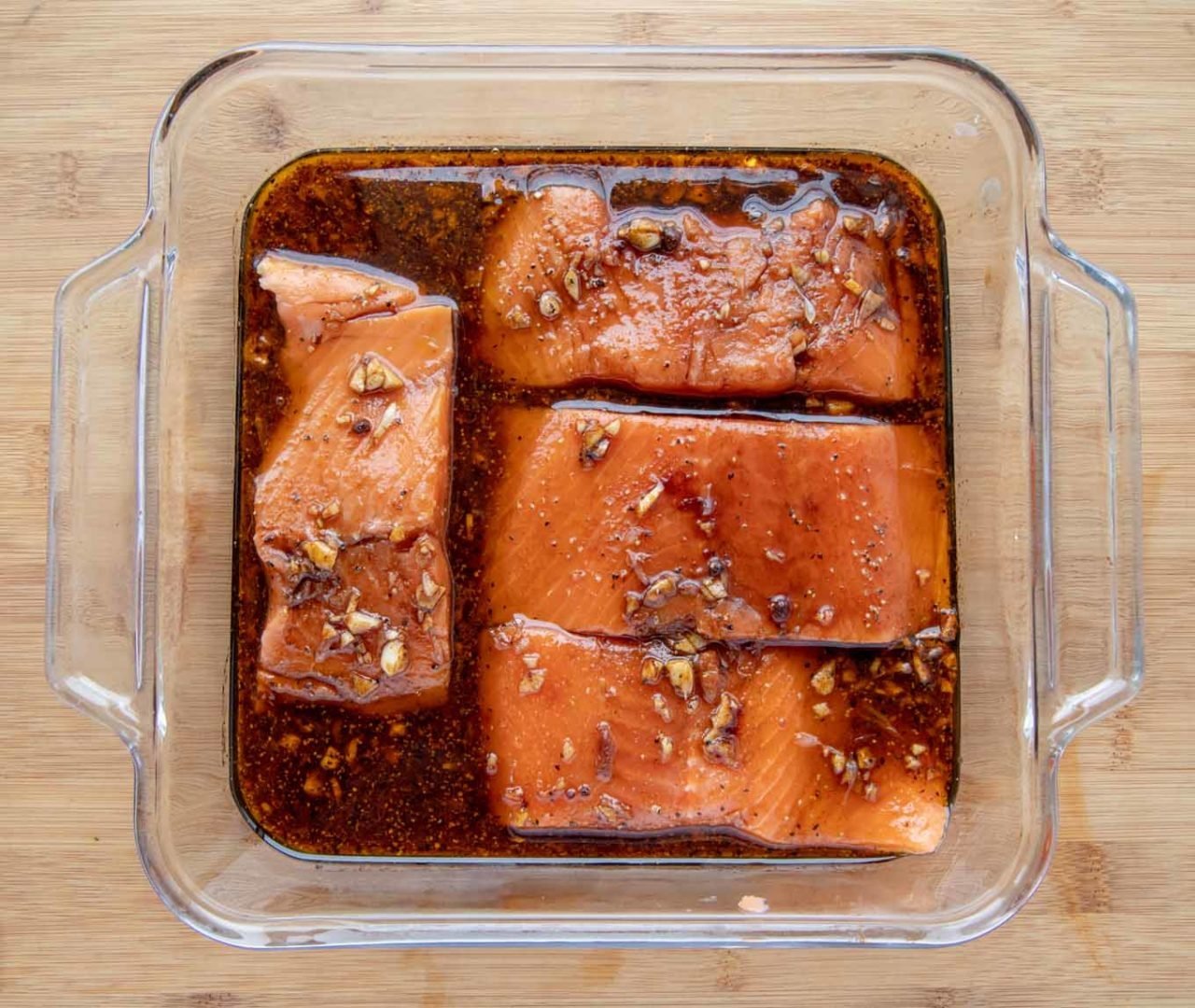 4 salmon filets marinating in a glass baking dish