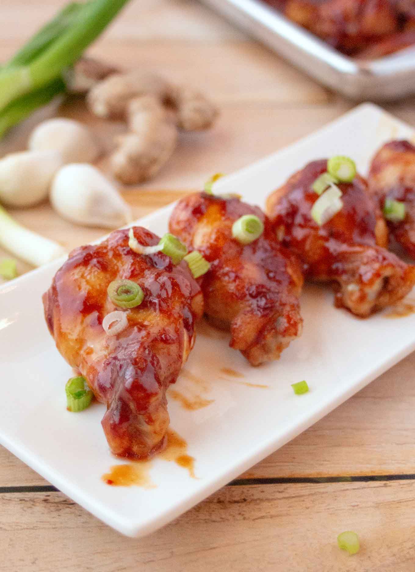 wings on a white platter garnished with sliced scallions