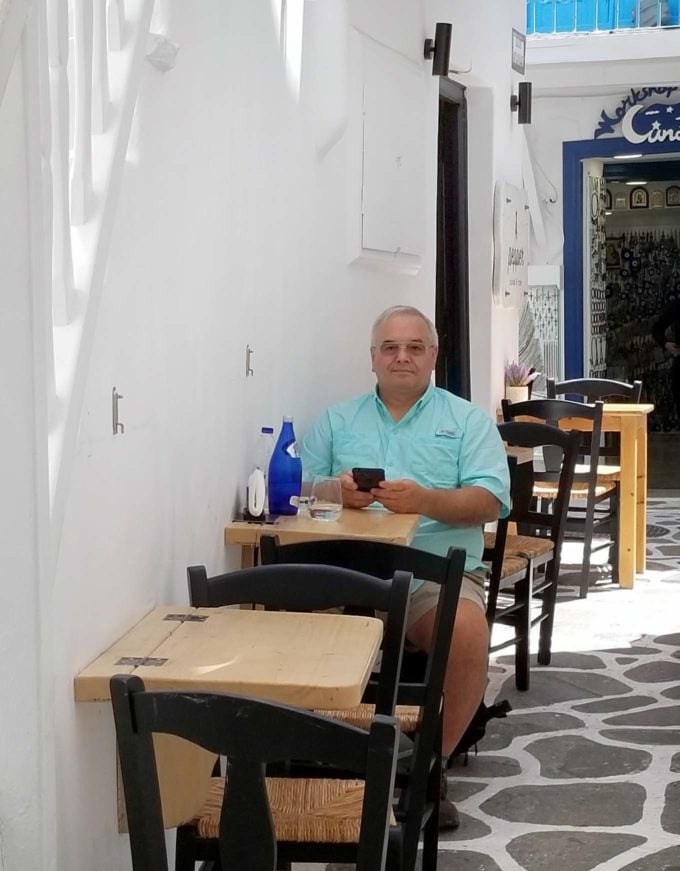 Chef Dennis sitting at a small table on a side street in Mykonos