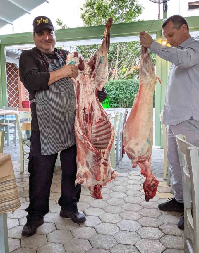 Chef and owner at the Stables Restaurant in Nafplio holding sides of Lamb