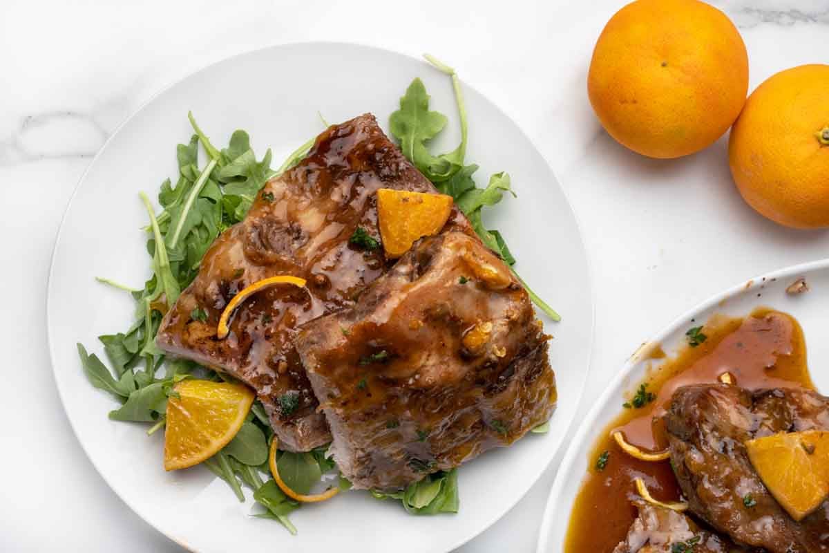 stack of double cut ribs on greens on a white plate