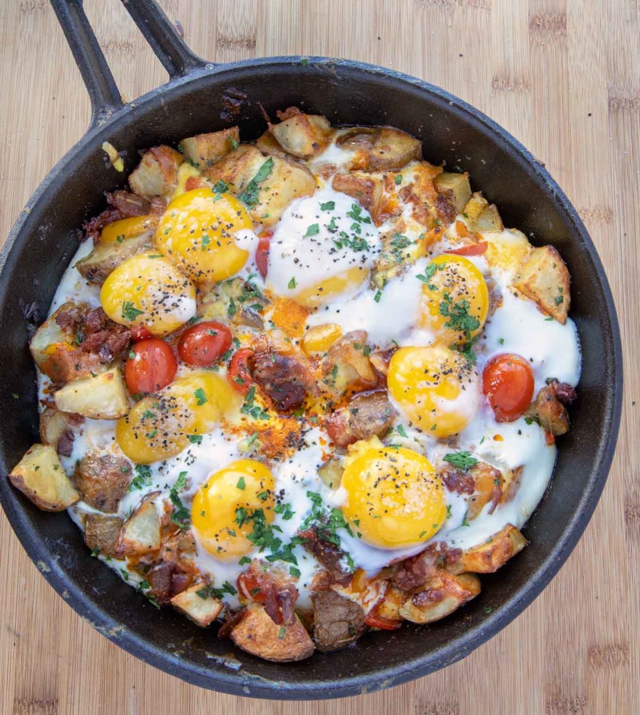 cast iron cheesy skillet breakfast with sunny side up eggs on top