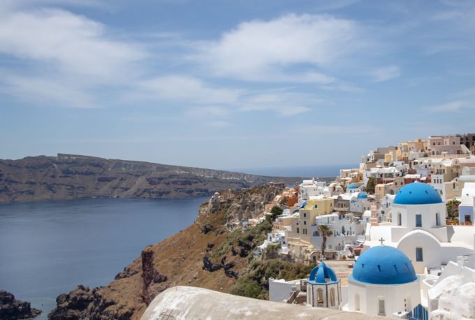 blue domes and white washed buildings on a hillside next to the sea in Oia, Mykonos
