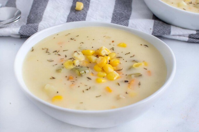 close up of corn chowder in a white bowl.