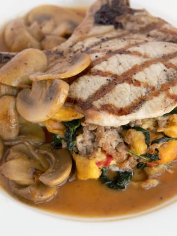 stuffed pork chop with mushroom gravy on a white plate