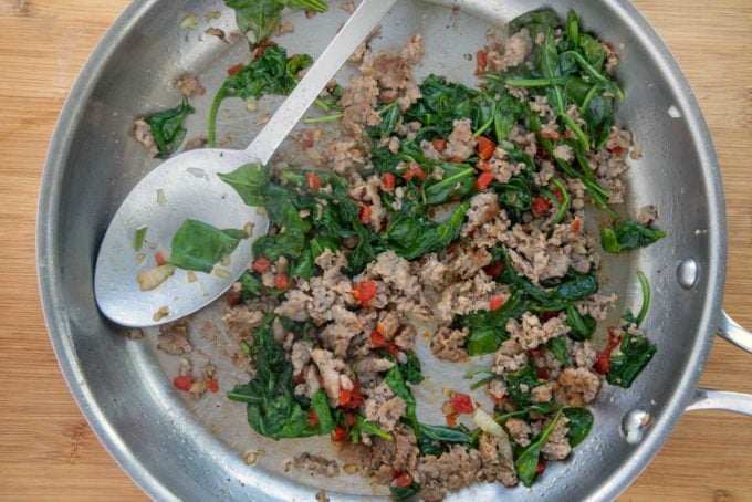 sausage meat and spinach for pork chop stuffing in saute pan