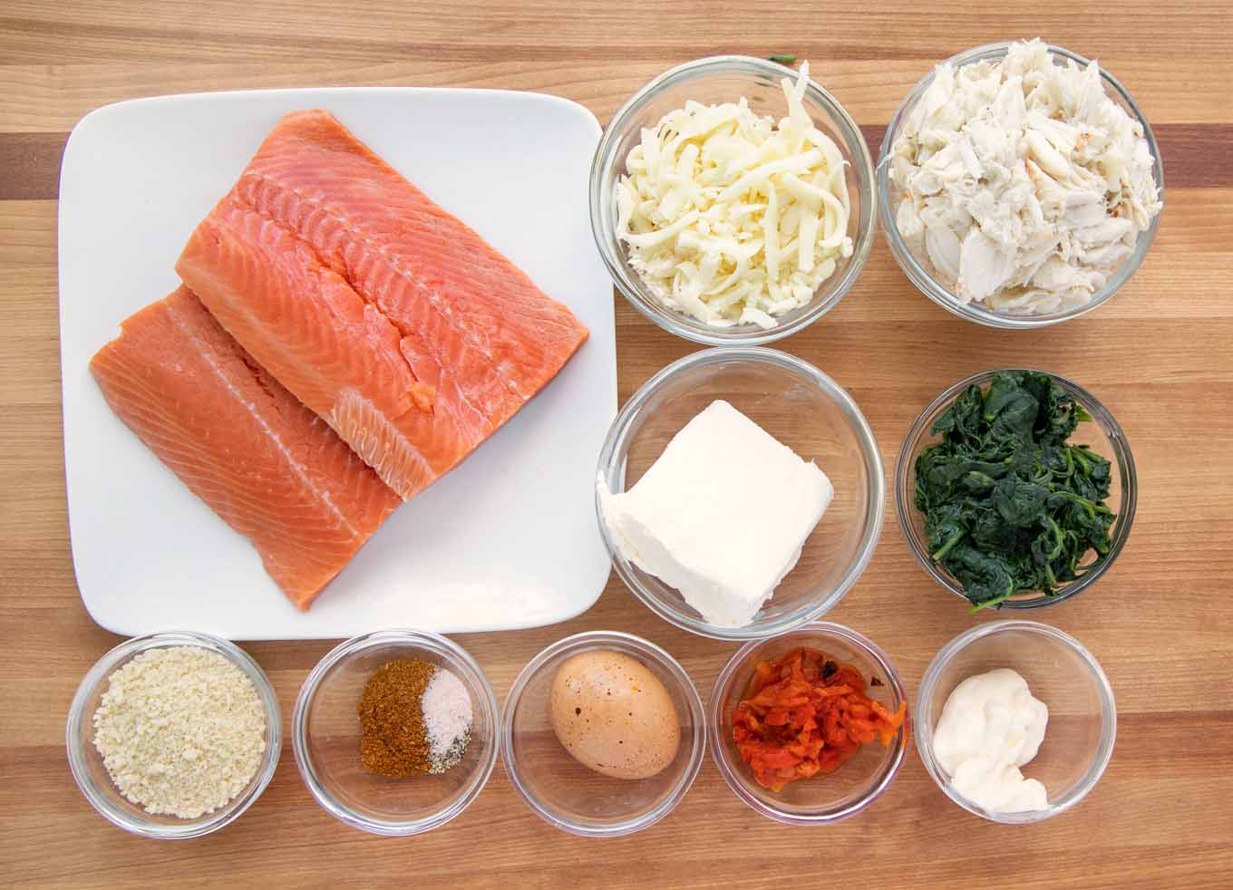 ingredients to make stuffed salmon in bowls on a wooden cutting board