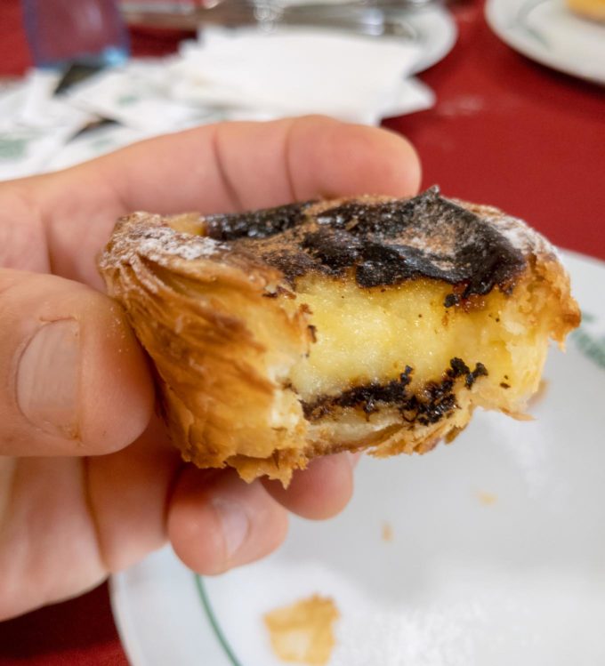 hand holding a Portuguese Custard Tarts (Pasteis de Nata) with a bite out
