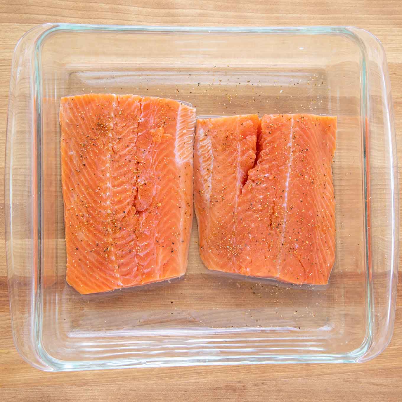  salmon fillets seasoned with sea salt and black pepper in a glass baking dish