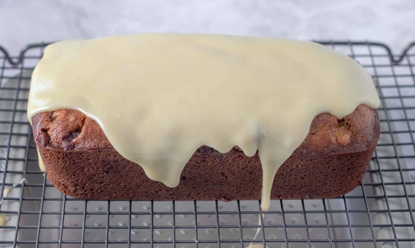 white chocolate ganache covering the top of the cannoli pound cake on a wire rack