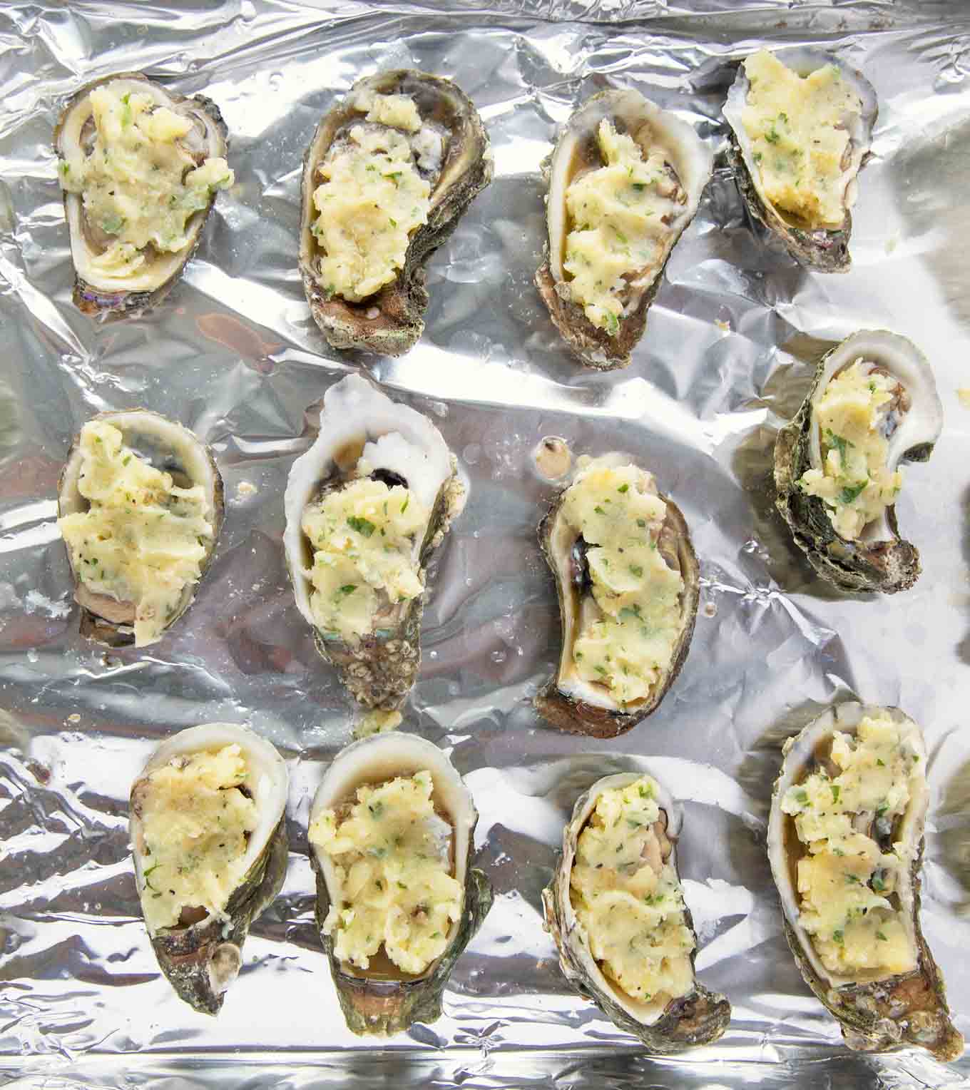 Oysters topped with garlic butter on a foil lined pan