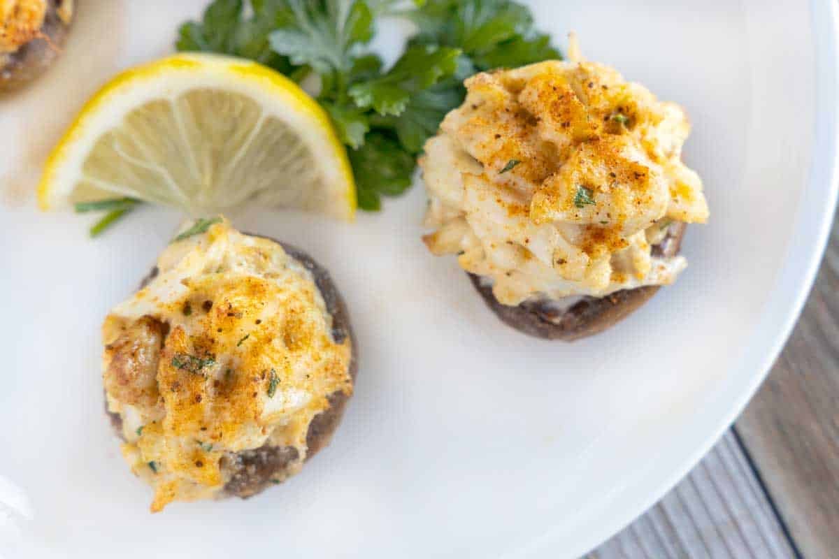 stuffed mushrooms on a white plate with lemon wedge