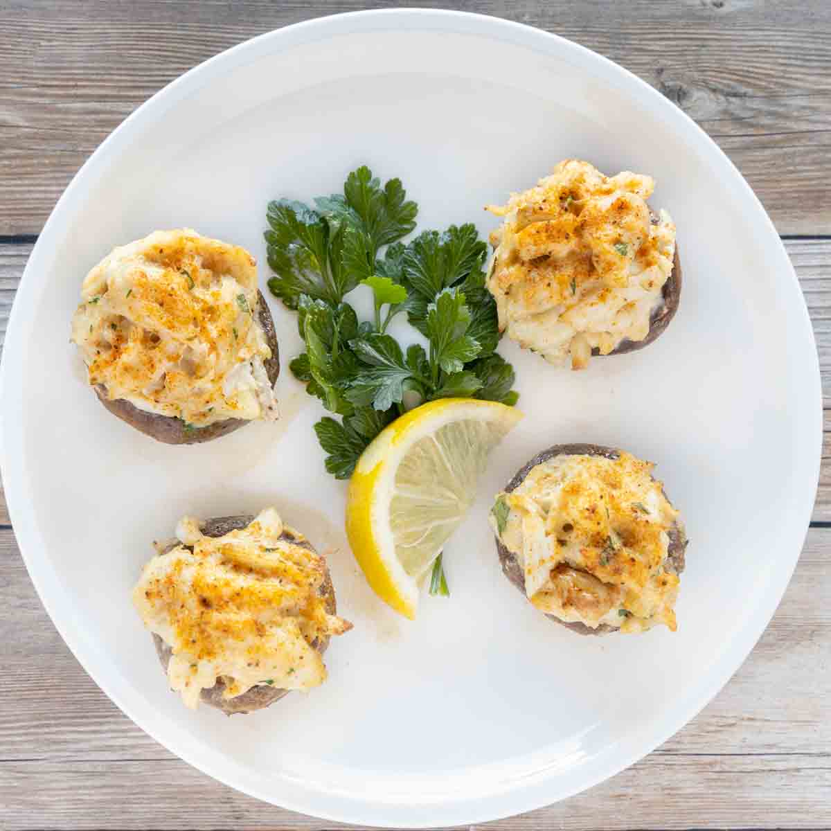 four crab stuffed mushrooms on a white plate