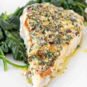 overhead view of a swordfish steak topped with garlic ginger topping on a bed of spinach on a white platter