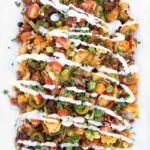 overhead shot of loaded tater tot nachos on a white platter
